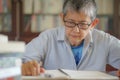 Older gray hair woman thoughtfully handwriting testament. Senior woman sitting at desk Royalty Free Stock Photo