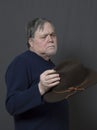 An older graying man inspecting a brown outback hat