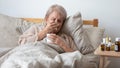 Older ill woman holding handkerchief blowing nose in bed Royalty Free Stock Photo