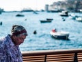 Creative Scene of an old woman from Rovinj, Croatia central Europe in midday, with beautiful boats bokeh balls useful for sample.