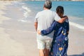 Older Latino couple walking on the beach in front of them