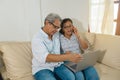 Older Latino web-surfing couple with laptop and cell phone.