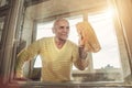 Older male person cleaning dirty window glass on balcony Royalty Free Stock Photo