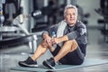 Older male rests with a bottle of water sitting on a mat during a gym workout