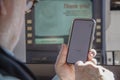 Older man attempting to use phone to complete a transaction at a drive up ATM machine - selective focus Royalty Free Stock Photo