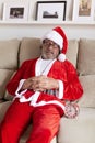 Older man dressed as Santa Claus tired. He has fallen asleep on the sofa