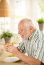 Older man eating pizza slice at home Royalty Free Stock Photo