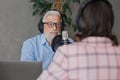 older man and female presenter in a recording studio create a podcast. senior, woman radio presenter or interviewer Royalty Free Stock Photo