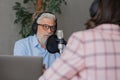 older man and female presenter in a recording studio create a podcast. senior, woman radio presenter or interviewer Royalty Free Stock Photo