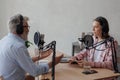 older man and female presenter in a recording studio create a podcast. senior, woman radio presenter or interviewer Royalty Free Stock Photo