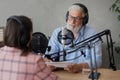 older man and female presenter in a recording studio create a podcast. senior, woman radio presenter or interviewer Royalty Free Stock Photo