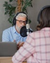 older man and female presenter in a recording studio create a podcast. senior, woman radio presenter or interviewer Royalty Free Stock Photo