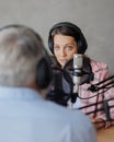 older man and female presenter in a recording studio create a podcast. senior, woman radio presenter or interviewer Royalty Free Stock Photo