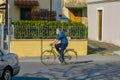 An older man with a green bicycle wears a surgical mask. Italian guy rides a bike in city.