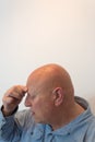 Older man head in profile hand to forehead, headache, bald, alopecia, chemotherapy, cancer Royalty Free Stock Photo