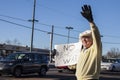 Older man at Iran anti-war protest waving and holding sign saying no re-election war