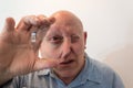 Older man looking through a large lens, distortion, bald, alopecia, chemotherapy, cancer, on white Royalty Free Stock Photo