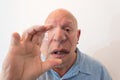 Older man looking over a large lens, distortion, bald, alopecia, chemotherapy, cancer, on white