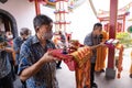 An Older man presenting the offerings in front of the monks while praying in the temple