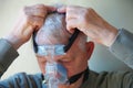 Older man puts on CPAP device head gear