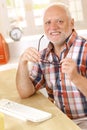 Older man putting on glasses at desk Royalty Free Stock Photo