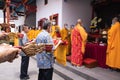 An Older man with the red tray waiting patiently for the chief monks to finish the praying