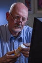 Older man refilling prescription online, vertical