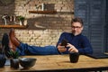 Older man sitting at desk using phone feet on desk Royalty Free Stock Photo