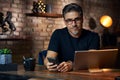 Older man sitting at desk using phone and tablet Royalty Free Stock Photo