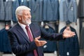 Older man smiling choosing costumes in store.