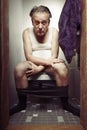 Older man on toilet in underwear spending time