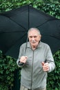 Older man with an umbrella under a stormy sky. old man with a mustache hides from the rain under an umbrella Royalty Free Stock Photo