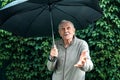 Older man with an umbrella under a stormy sky. An old man with a mustache hides from the rain under an umbrella Royalty Free Stock Photo