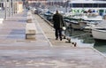 An older man walks along attached boats in port Tarragona. Spain 04.01. 2016