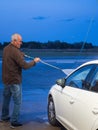 Older man washing car with pressure hose Royalty Free Stock Photo