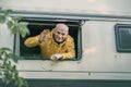 Older man waving out of window of his camper in style of adventure themed and transfer