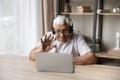 Older man wear headset start videoconference seated at table