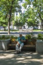 An older man wearing an anti Covid-19 mask reading outside the fence of the Royal botanical gardens In Madrid