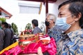 An Older man wearing a white mask while holding a tray and praying in pandemic