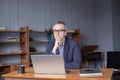 Older man working online with laptop computer at home sitting at desk. Home office, browsing internet. Portrait of mature age, Royalty Free Stock Photo