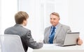 Older man and young man signing papers in office