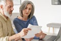 Older mature couple checking bank documents or bills using laptop at home. Royalty Free Stock Photo