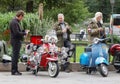 Older men dressed as mods posing at their retro vespa scooters