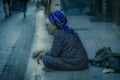 Older Moslem woman sits on street in poverty, Luxor Souq, Egypt