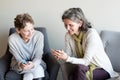 Older mother and daughter smiling with smartphones