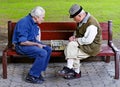 Older people play chess on a bench