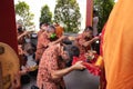 An older person bow down to the ground while praying and holding the offering orange tray