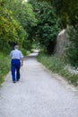 older person man walking with cane to perform daily walking exercise on dirt road with vegetation