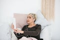 An older positive woman uses a tablet to watch videos, listen to music and chat with friends on social networks. Royalty Free Stock Photo