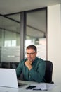 Older professional business man looking at laptop working in office. Vertical. Royalty Free Stock Photo